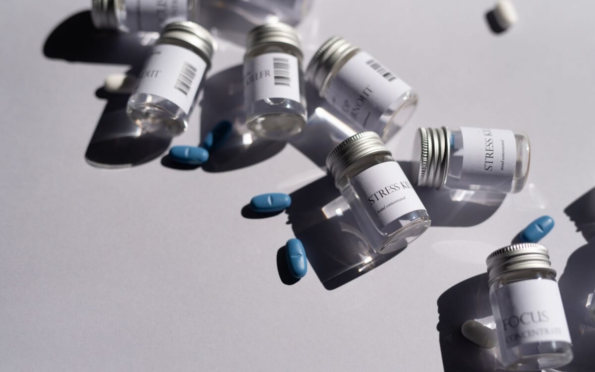 Close-up de garrafas de medicamentos e pílulas azuis em fundo branco, enfatizando saúde