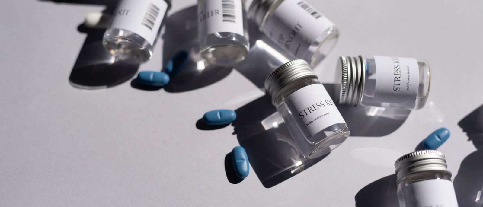 Close-up de garrafas de medicamentos e pílulas azuis em fundo branco, enfatizando saúde