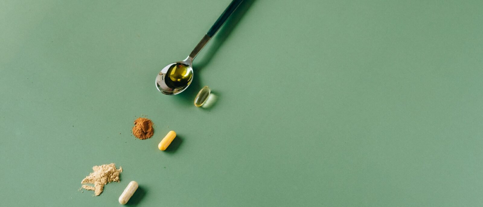 Suplementos e pós fitoterápicos variados em fundo verde com uma colher
