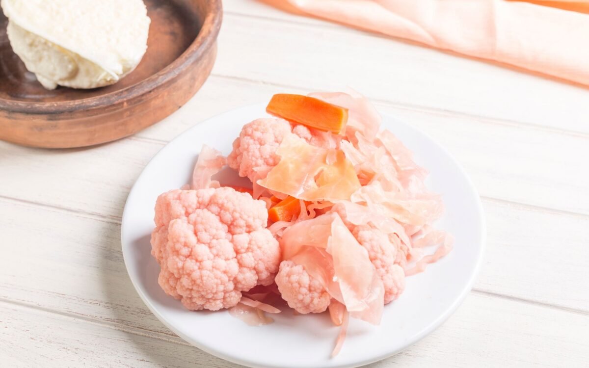 Couve-flor e cenoura em conserva rosa em prato branco, perfeitas para apresentações culinárias