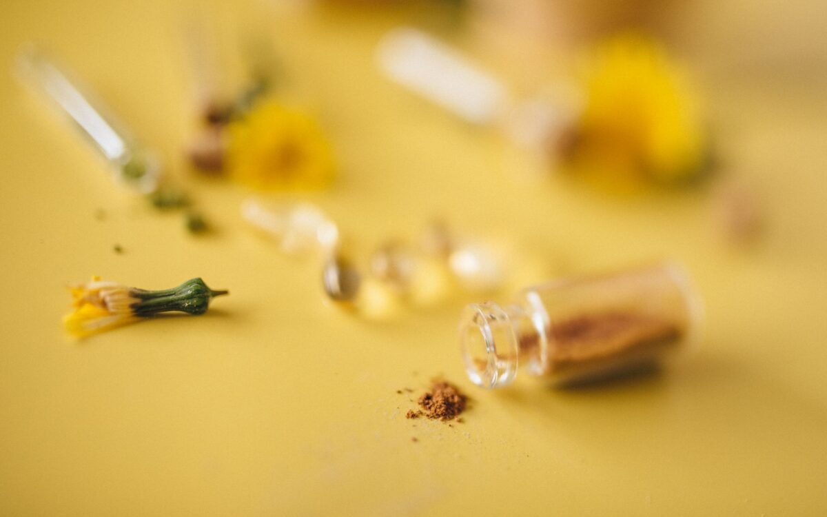 Detalhe de pó herbal e flores sobre superfície amarela, conceito de remédios naturais
