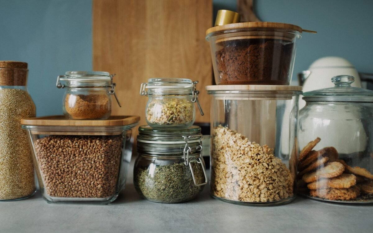 Dispensa elegante com variedade de alimentos em potes de vidro, exibindo secos e biscoitos